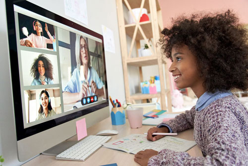 African American girl looking at computer screen showing faces in an online meeting