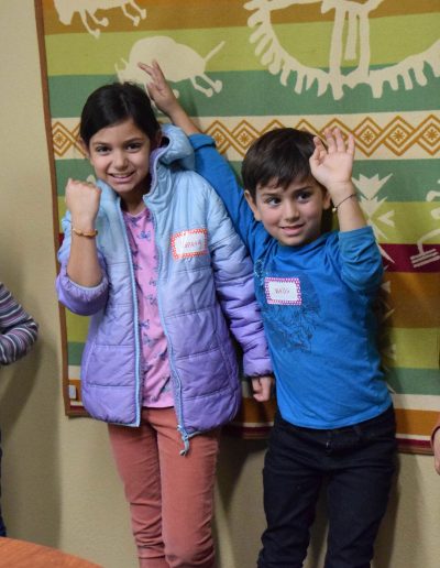 Four kids holding their arms in the air to show the bracelets they made at Sierra Native Alliance