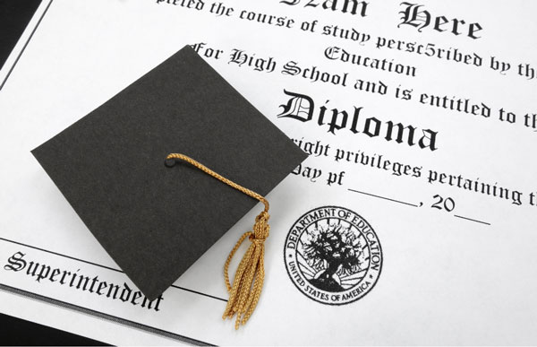 diploma closeup photo of a document that says diploma with a small black graduation cap and tassle on top of it